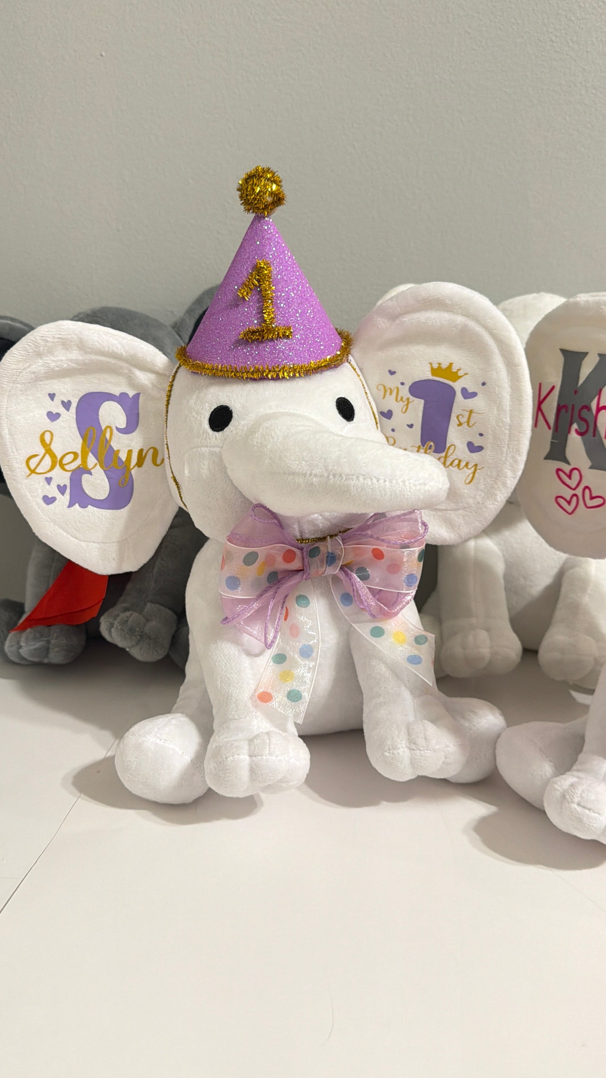 Custom stamped 'My First Birthday' plush elephant keepsake arranged as an upscale toddler milestone gift.