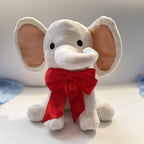 Plush elephant toy with a red bow on a light background